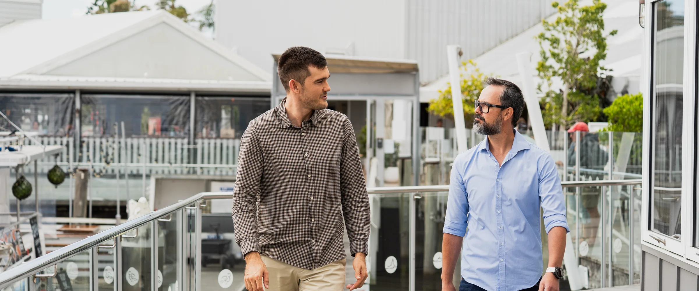 Two engineers in conversation walking along a waterfront boardwalk on the Sunshine Coast